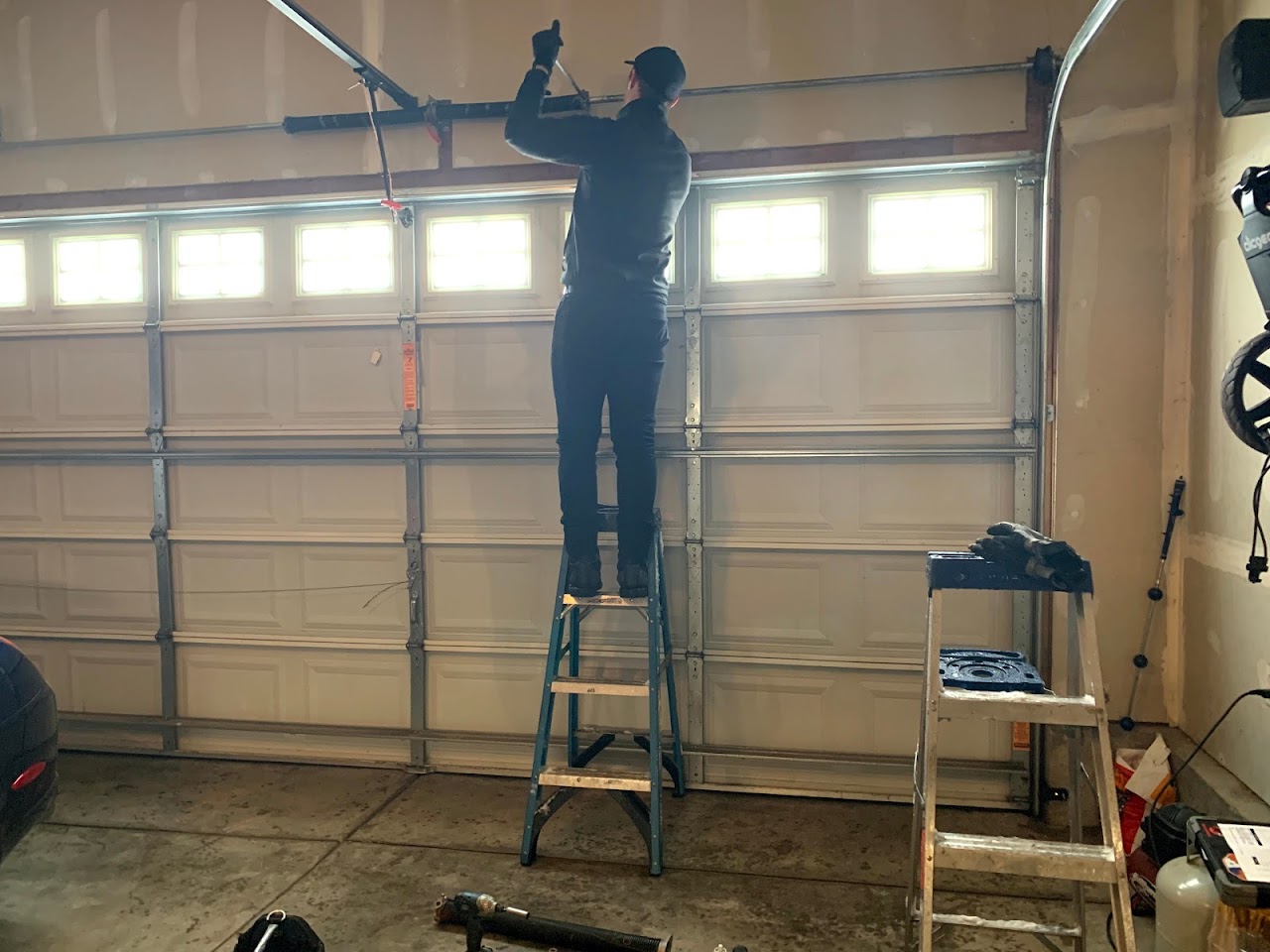 Academy Overhead Door technician on a ladder installing a white garage door